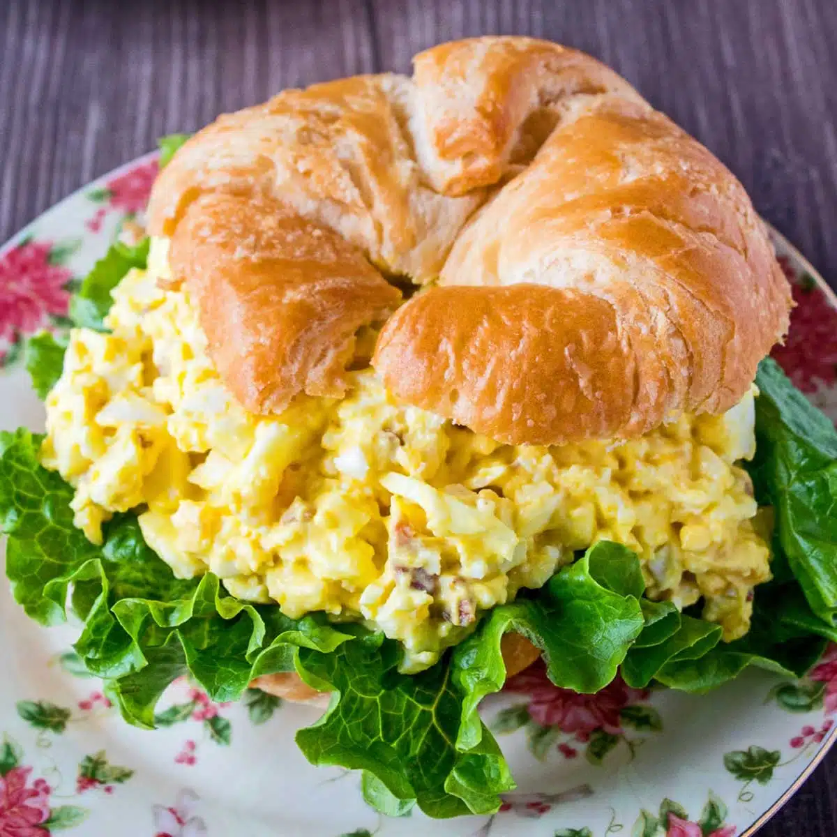 Egg salad sandwich on a floral plate.