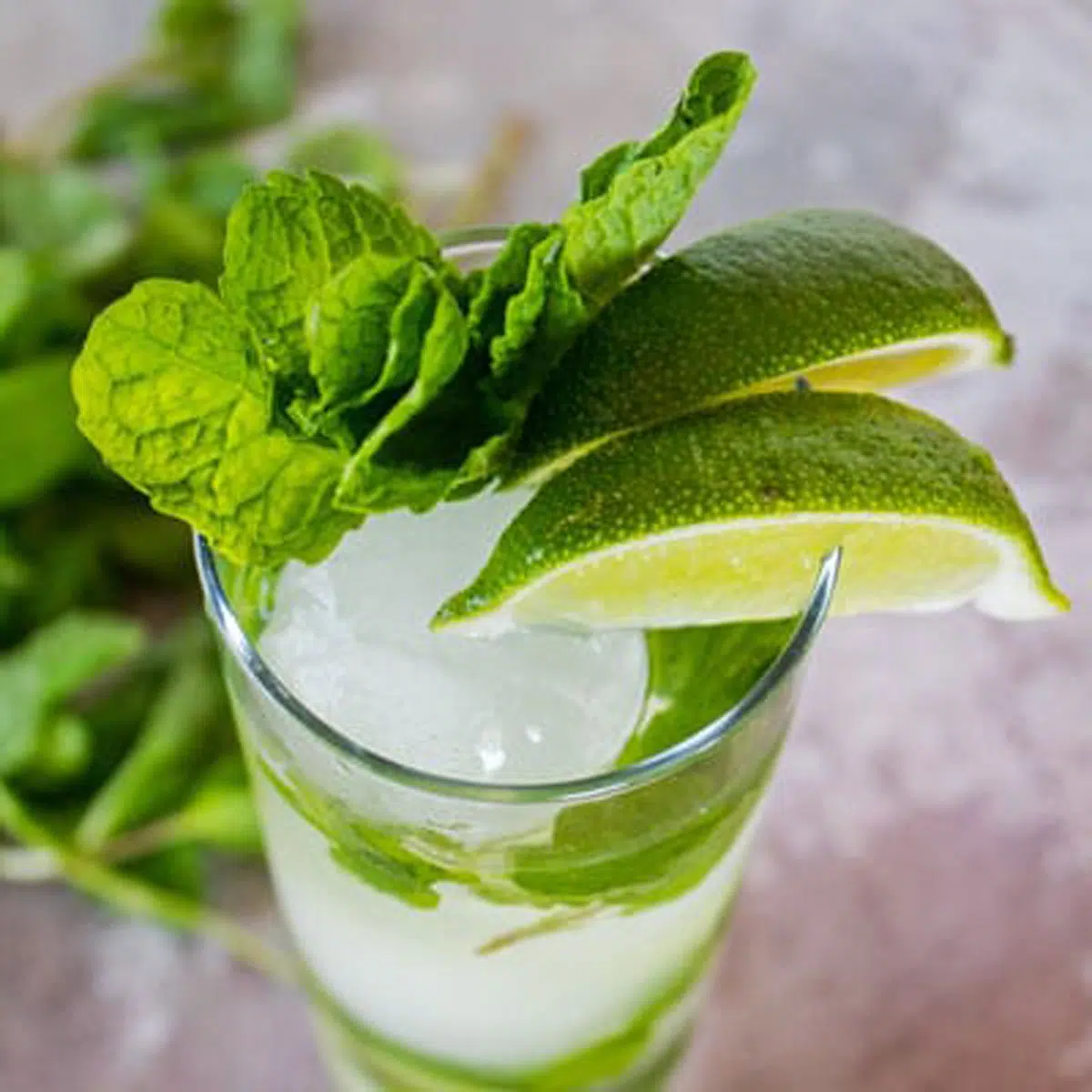 Angled picture of a glass of mojito, with ice, limes, and mint.