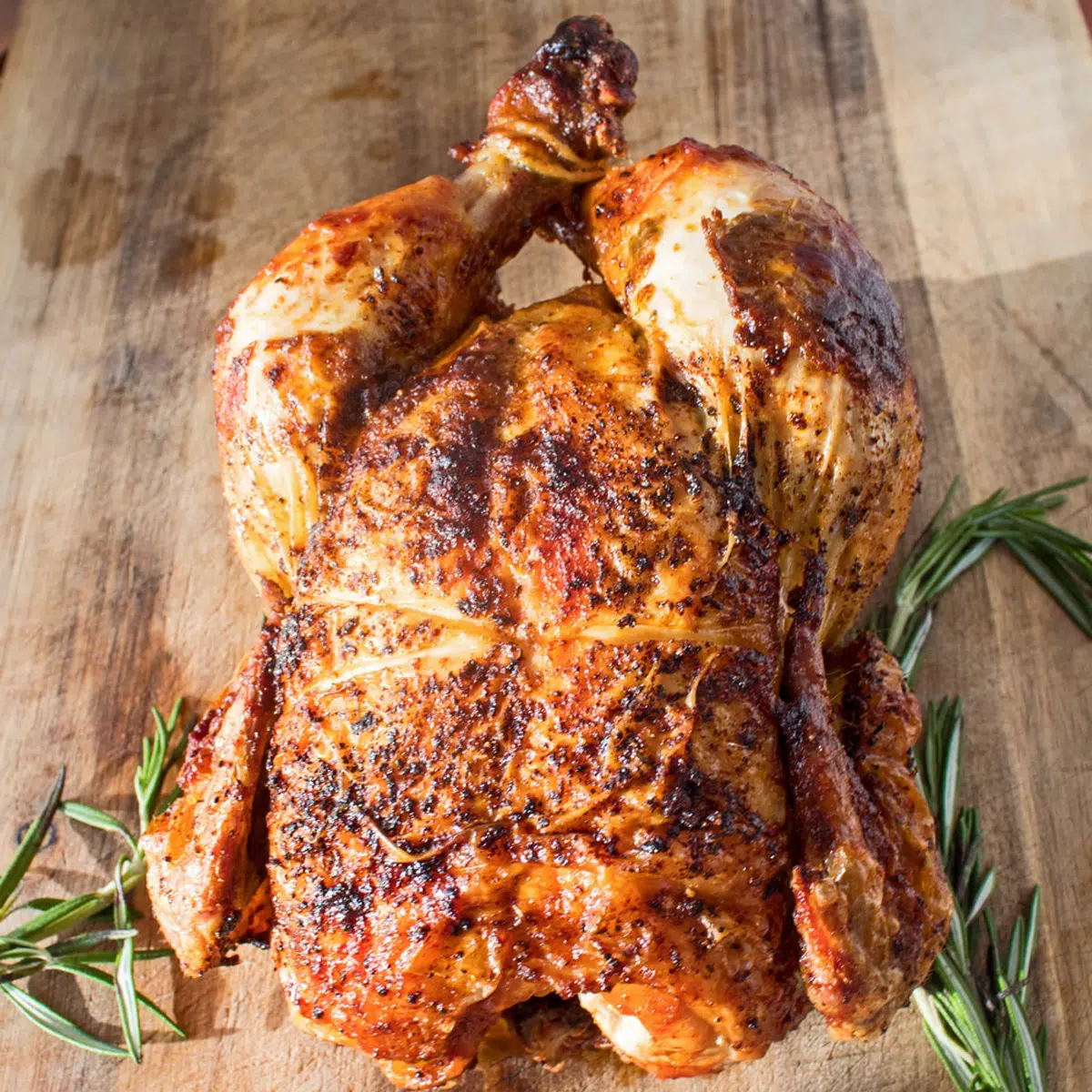 Rotisserie chicken on a cutting board with fresh rosemary.