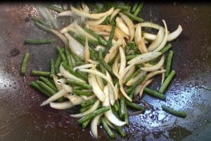 add string beans or green beans to the onions and continue to stir fry