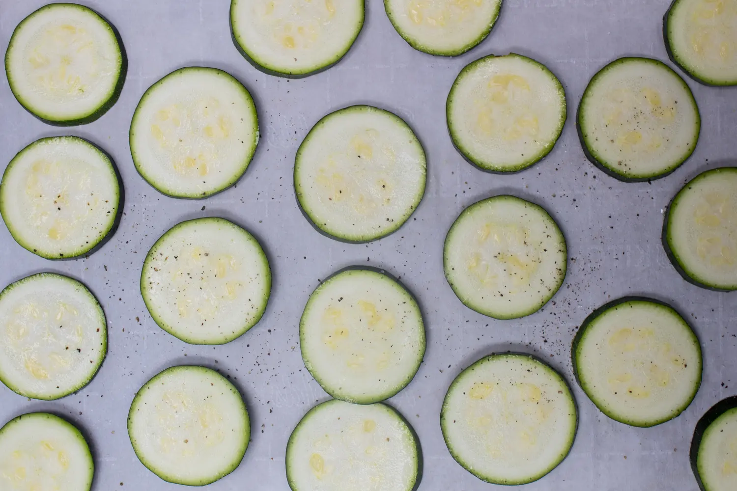 zucchini sliced in rounds laid out on baking sheet and seasoned with salt and pepper