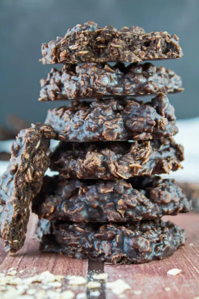 cooled and set chocolate peanut butter no bake cookies are ready to eat, stacked here in a set of 6 cookies with an opened cookie leaning against the left side