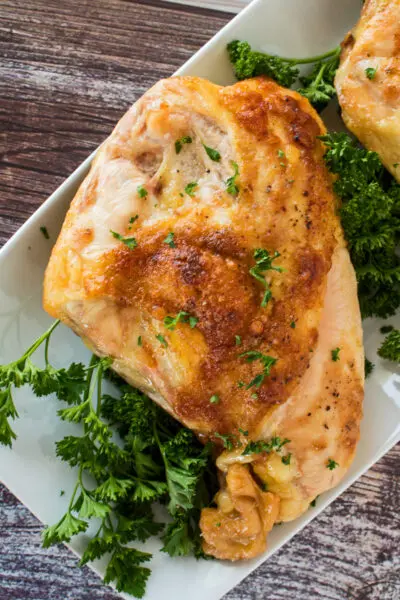 larger zoomed in view of the same chicken breast garnished with fresh parsley