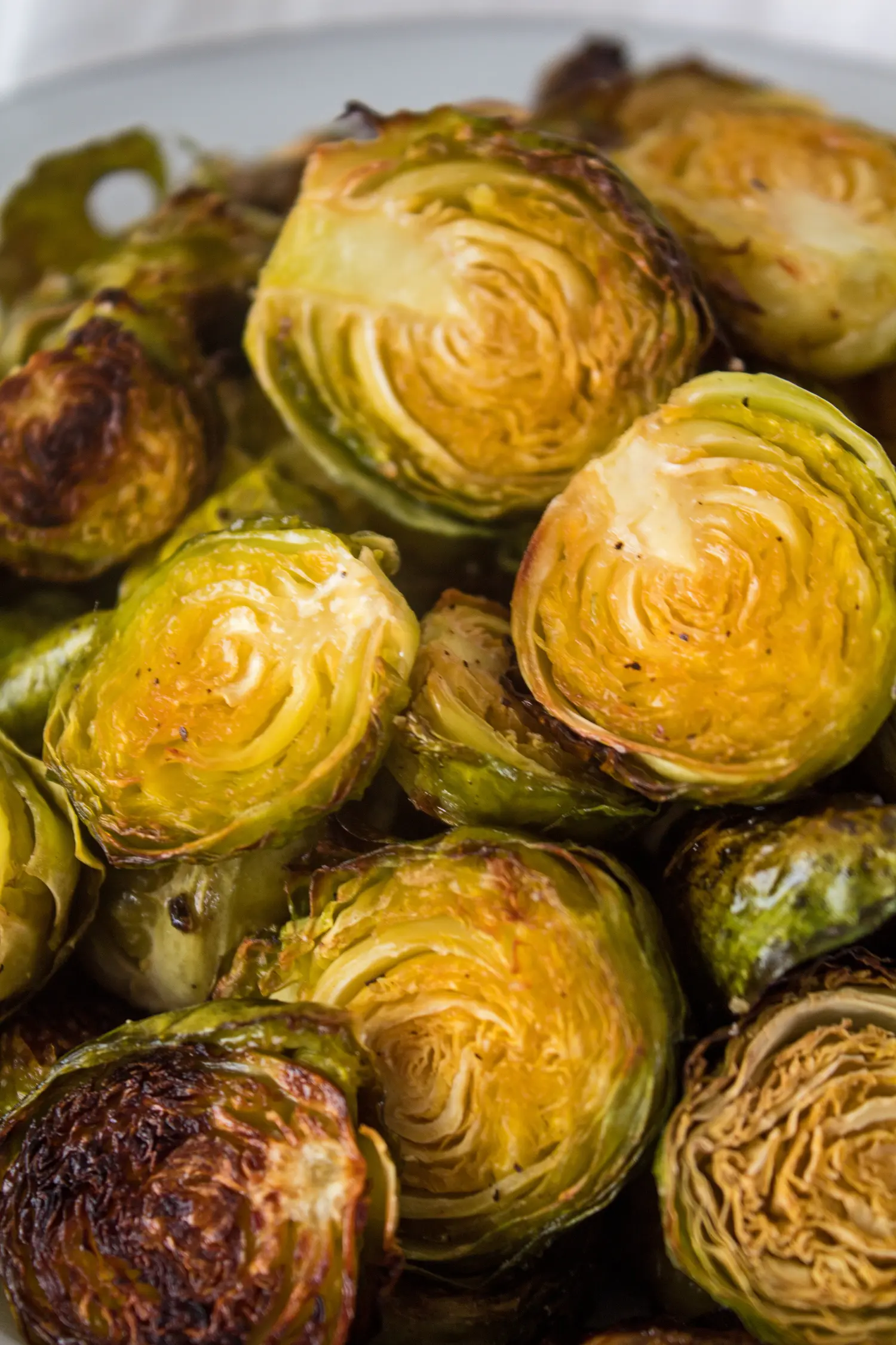 Close up vertical image of roasted brussel sprouts showing golden caramelized color.