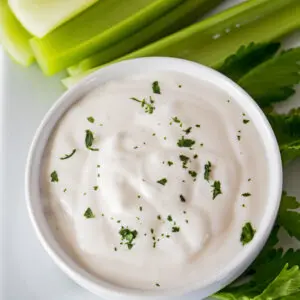 overhead image of homemade blue cheese dressing served in a white bowl with cut celery in the background