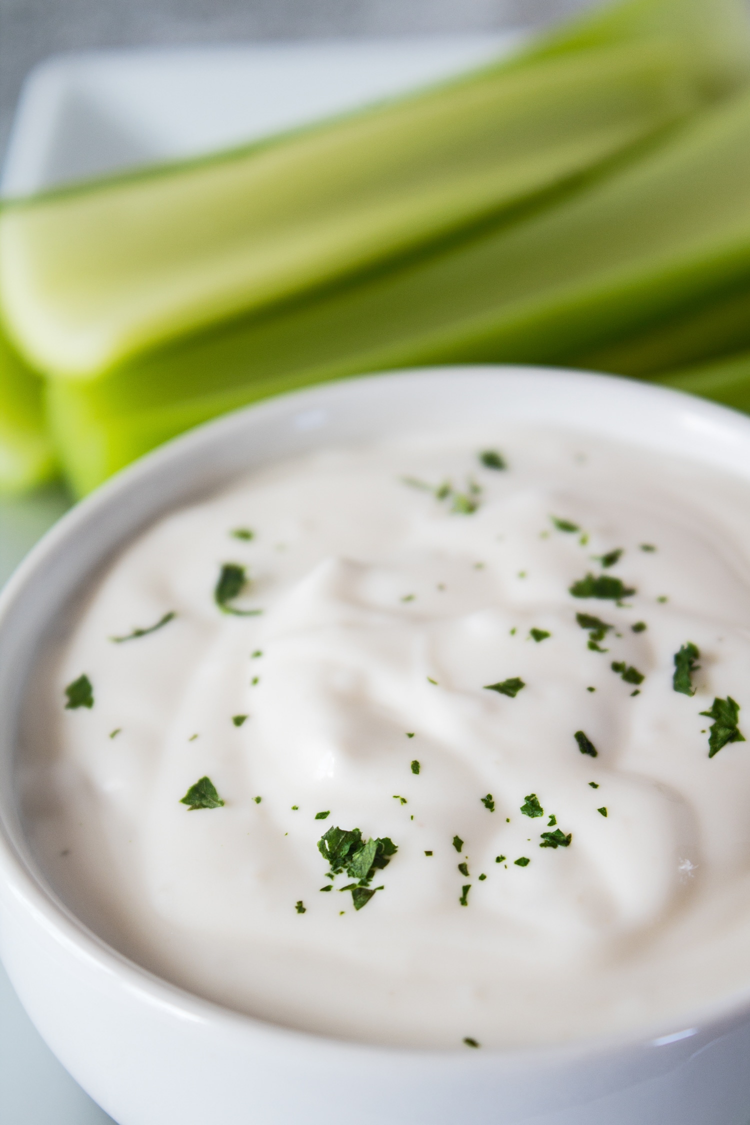 closeup image of the homemade blue cheese dressing in a white bowl with cit celery in the background