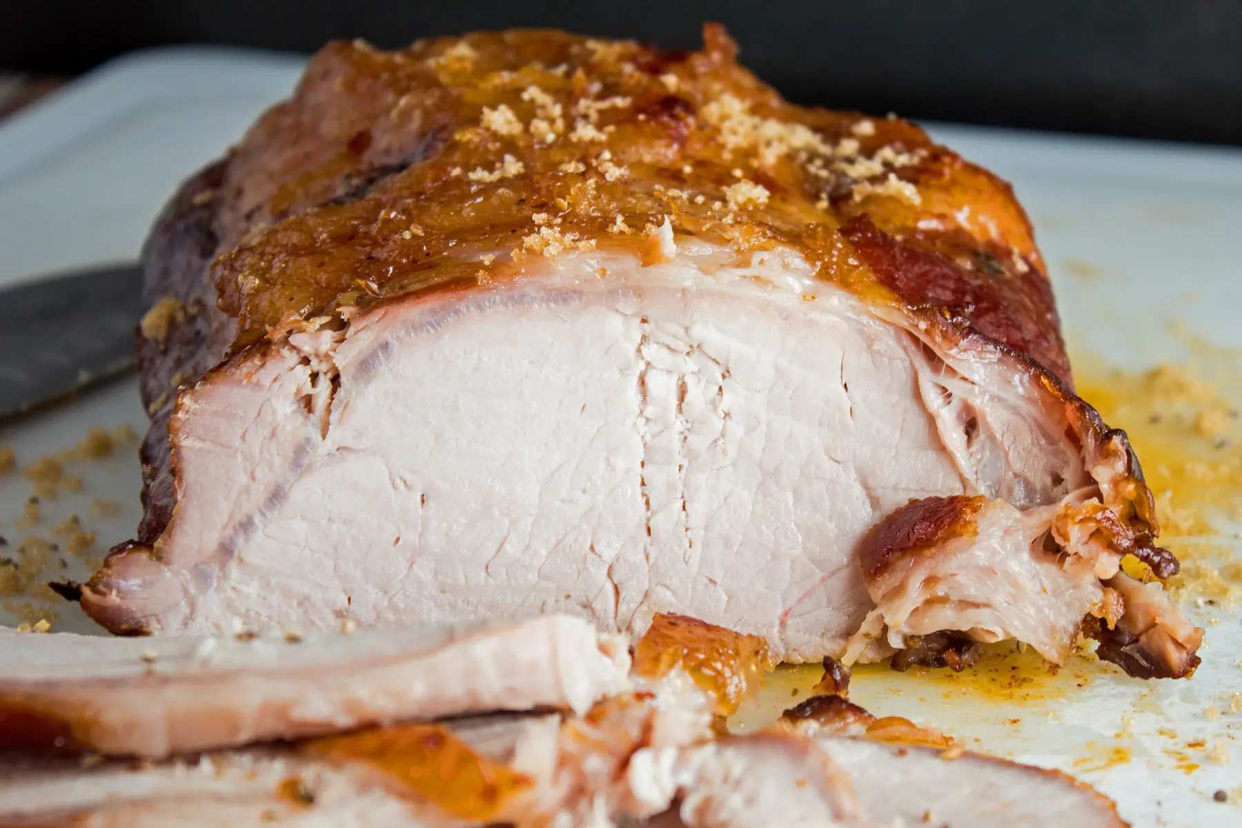 a close up image of apple cider marinate smoked pork loin with several slices cut away to show the tender, juicy smoked pork loin roast