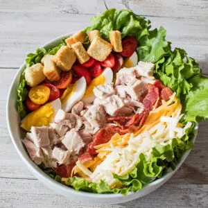 overhead image of the chef salad in a large white serving bowl on a grey wooden background as the larger featured image