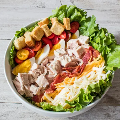 overhead image of the chef salad in a large white serving bowl on a grey wooden background