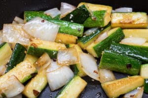 zucchini and onion with seasoning being cooked hibachi style