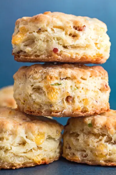 tall image of stacked tasty cheddar bacon chive biscuits freshly baked and ready to enjoy