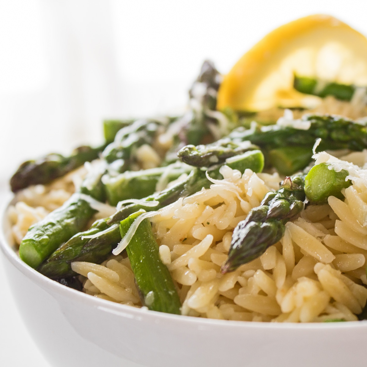 Large square photo being a closeup sideview of the dished lemon asparagus orzo pasta.