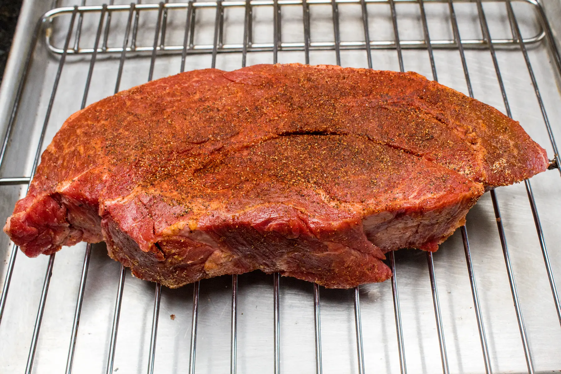 beef chuck roast seasoned with a dry rub and ready to transfer the rack and roast into preheated smoker