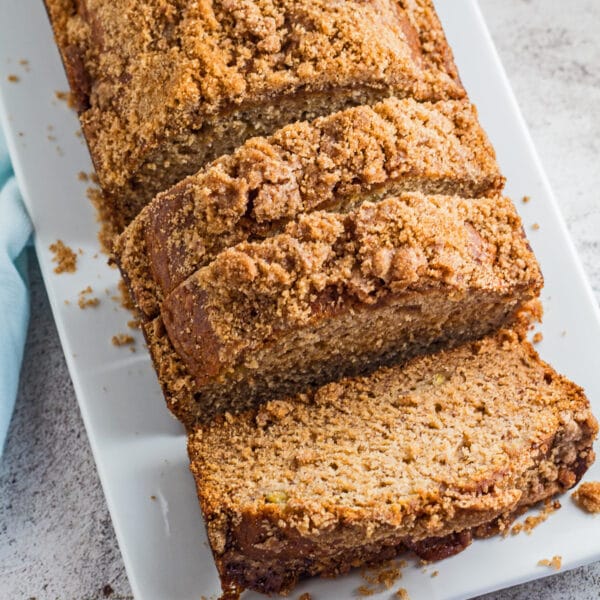 large square angled overhead image of the sliced banana bread with brown sugar streusel topping served on white plate.