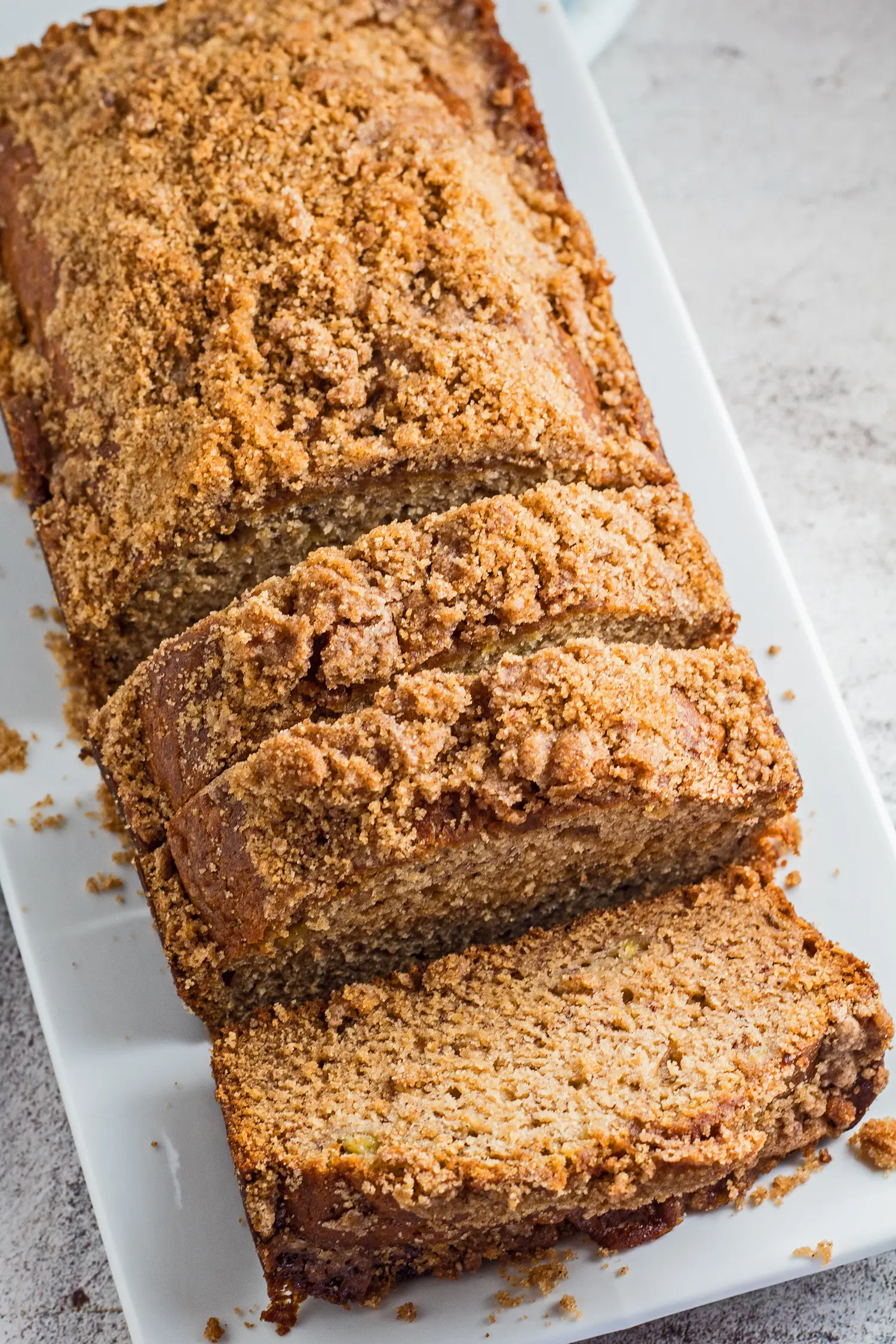 tall angled overhead image of the sliced banana bread with brown sugar streusel topping served on a white plate.