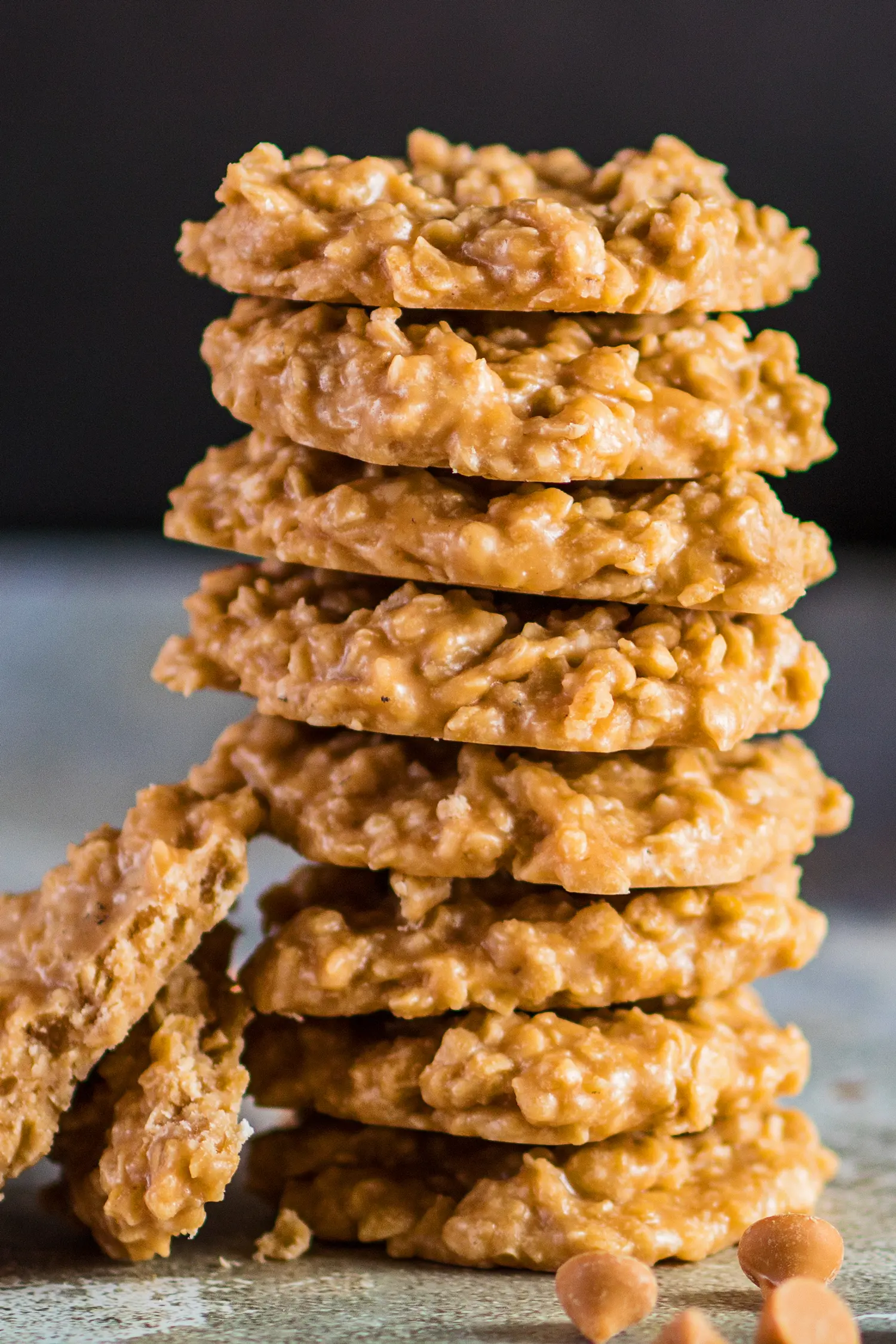 closeup tall image of the butterscotch no bake cookies stacked with morsels around them.