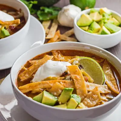 perfect chicken tortilla soup with garnish served in white bowls.