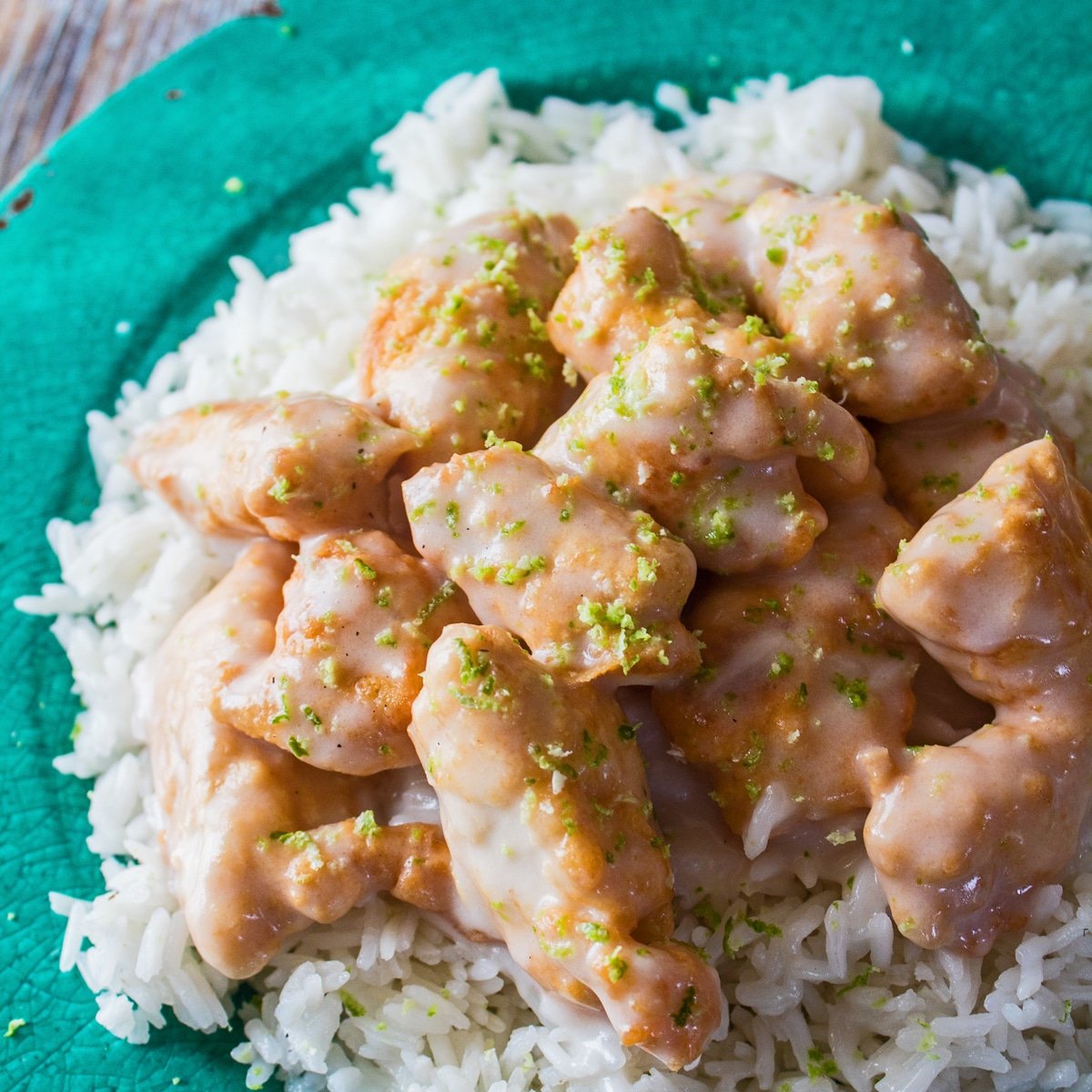 Gran ángulo de arriba cuadrado del pollo servido con arroz en un plato verde.