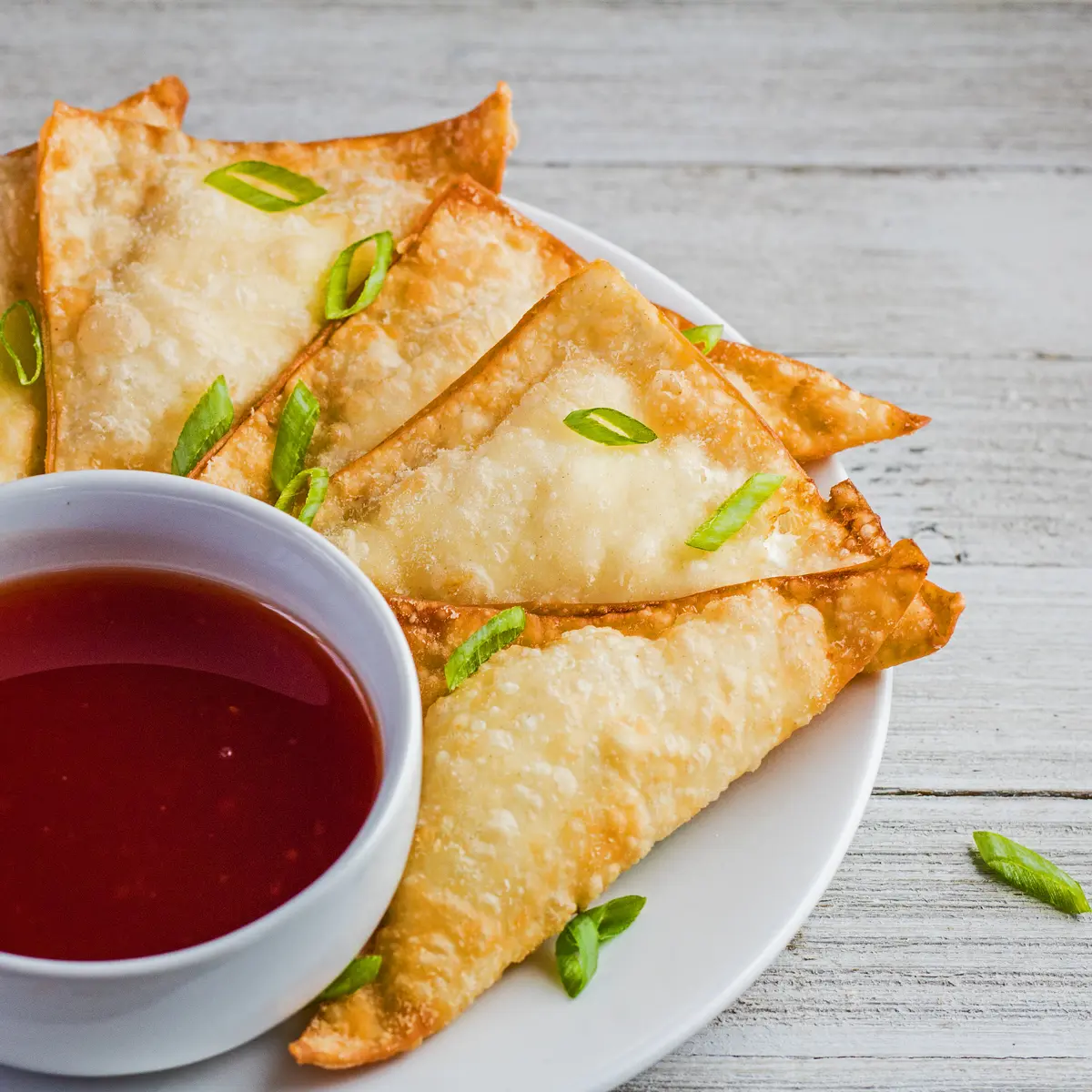 large square angled overhead image of the plated cream cheese wontons with sweet and sour sauce for dipping.