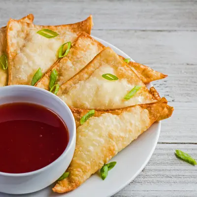 small square angled overhead image of the plated cream cheese wontons with sweet and sour sauce for dipping.