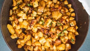 breed bovenaanzicht van de in de pan gebakken aardappelen en uien in de koekenpan.