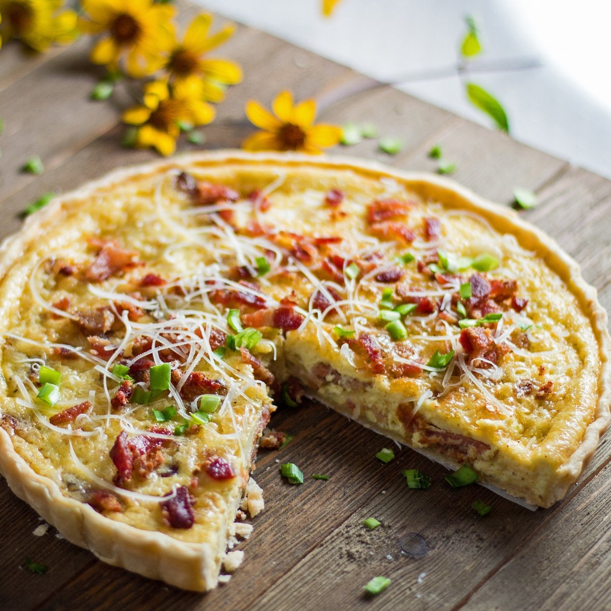large square image baked quiche lorraine sliced and being served