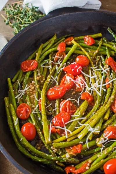 tall overhead image of the asparagus and tomatoes in cast iron skillet.