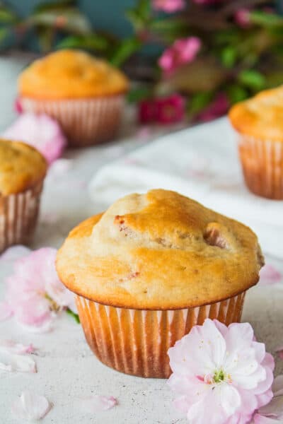 tall angled overhead image of the strawberry muffins on a light background with flowers.