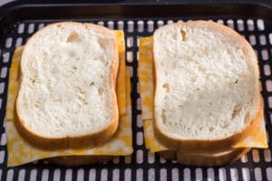 sandwich keju panggang yang telah dirakit sepenuhnya siap untuk dimasukkan ke dalam penggorengan udara.