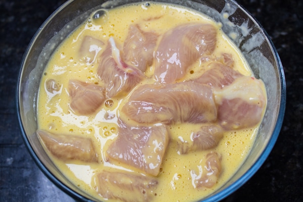 cut chicken pieces soaking in marinade before refrigerating.