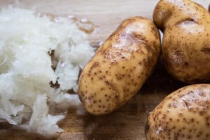 cebolla rallada y patatas lavadas listas para cortar en dados y echar a la sartén.