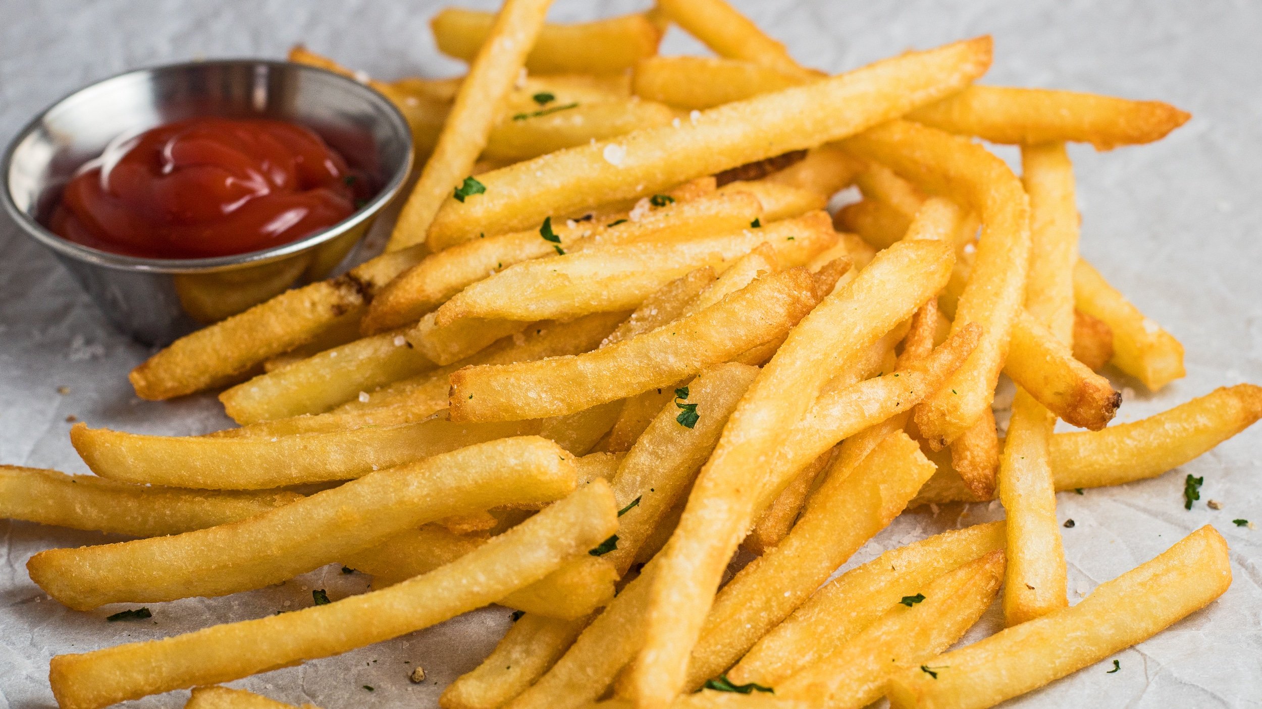 breed beeld van bevroren frietjes uit de luchtfriteuse geserveerd met ketchup.