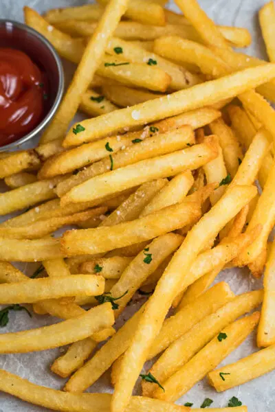 tall angled overhead view of air fryer frozen french fries served with salt and ketchup.