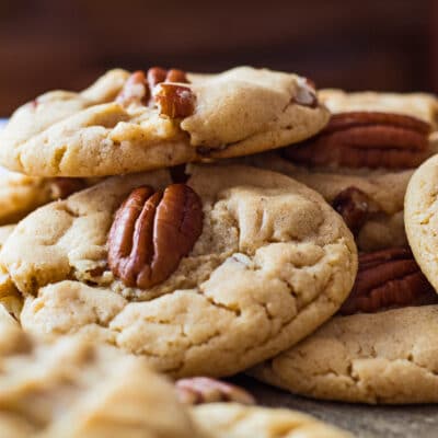 Large square image of loosely piled peanut butter pecan cookies.