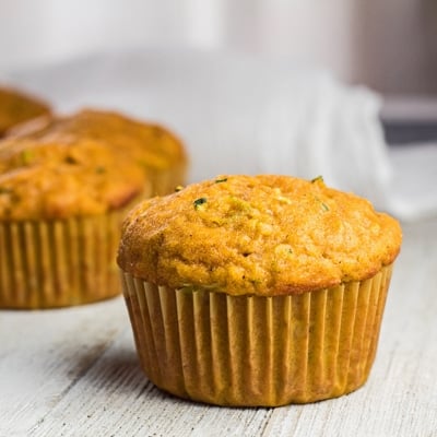 small square image of pumpkin zucchini muffins on light background.