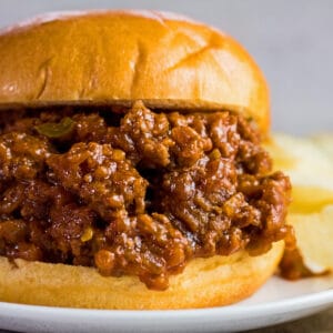large square closeup image of sloppy joes on buns with chips.
