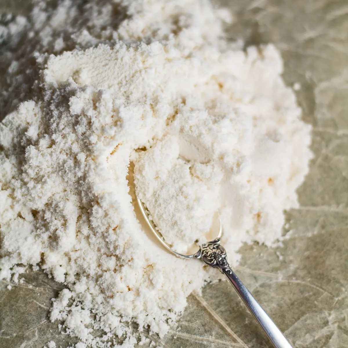large square overhead image of loose arrowroot powder on paper background.