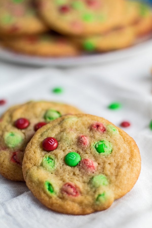 angled overhead image of Christmas M&M Cookies with a plate for Santa in the background.