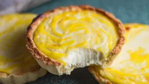 wide closeup image of the hokkaido cheese tarts with a bite showing the creamy texture.