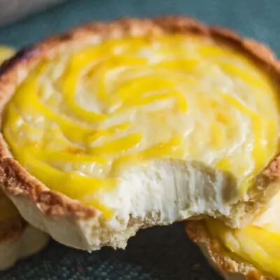 wide closeup image of the hokkaido cheese tarts with a bite showing the creamy texture.