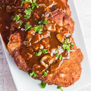 Large square angled overhead image of jagerschnitzel served on white plate.