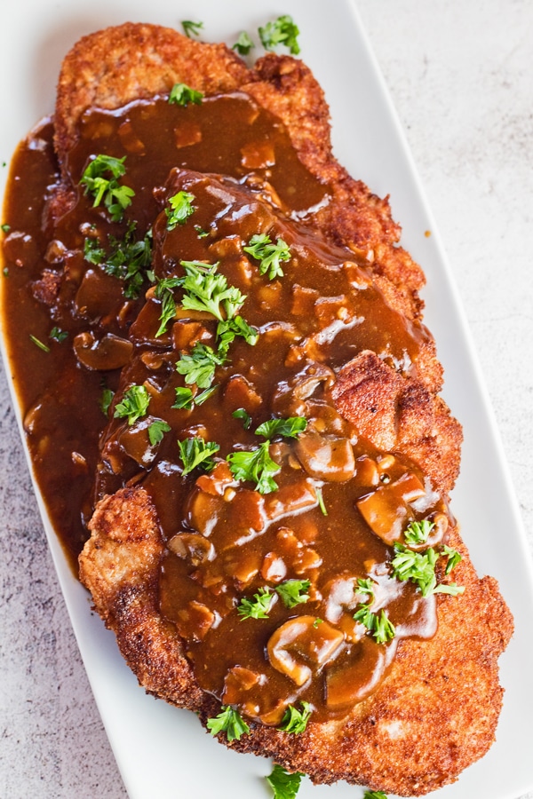tall overhead image of the dished jagerschnitzel on light background.