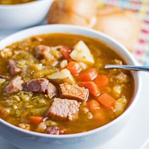 Grote vierkante schuine overhead afbeelding van sopa de chicharos geserveerd in witte kom.