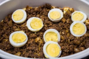 layering the seasoned beef and hard-boiled eggs into the casserole.