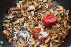 обжаренные грибы и бекон с приправой и томатной пастой.