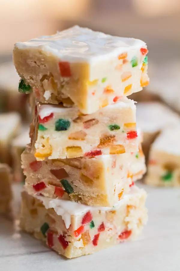 tall image of four fruitcake shortbread squares stacked in front of the rest of the batch.