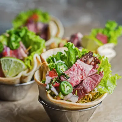 large square angled frontview of the leftover prime rib tostadas in metal dipping sauce cups.