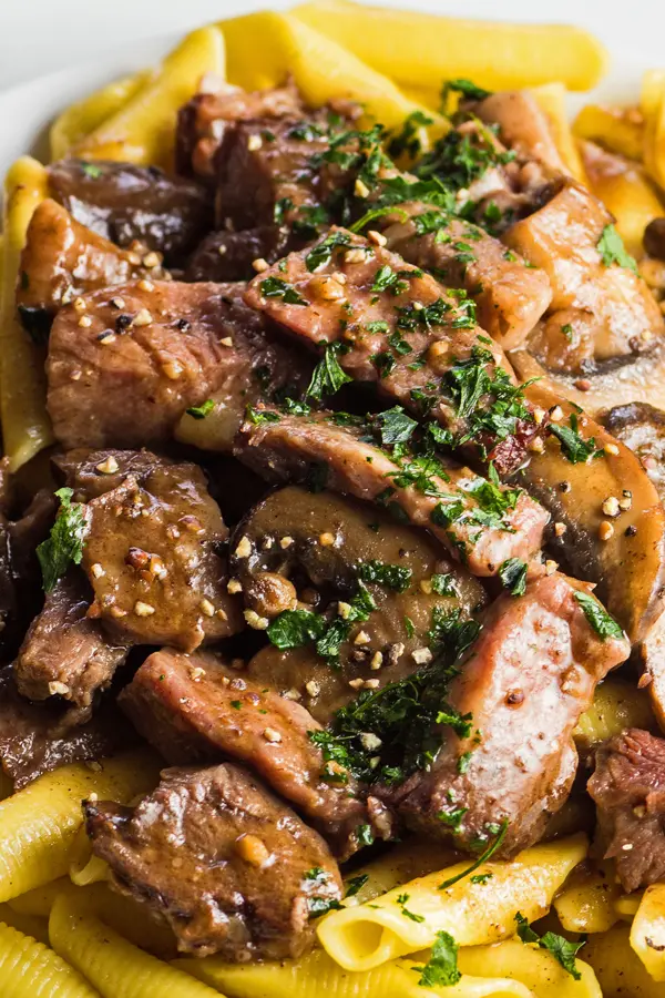 wide vertical closeup overhead view of the prime rib pasta with mushroom garlic gravy.