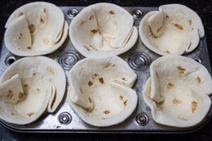 tortilla ukuran jalanan taco dipasang ke dalam loyang muffin.