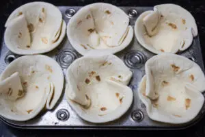 street taco sized tortillas fitted into muffin pan.